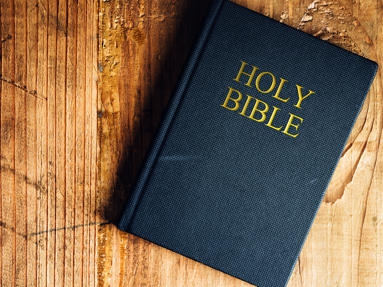 Holy Bible on old wooden church table, top view