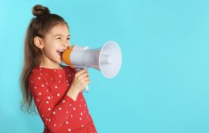 Cute funny girl with megaphone on color background. Space for text